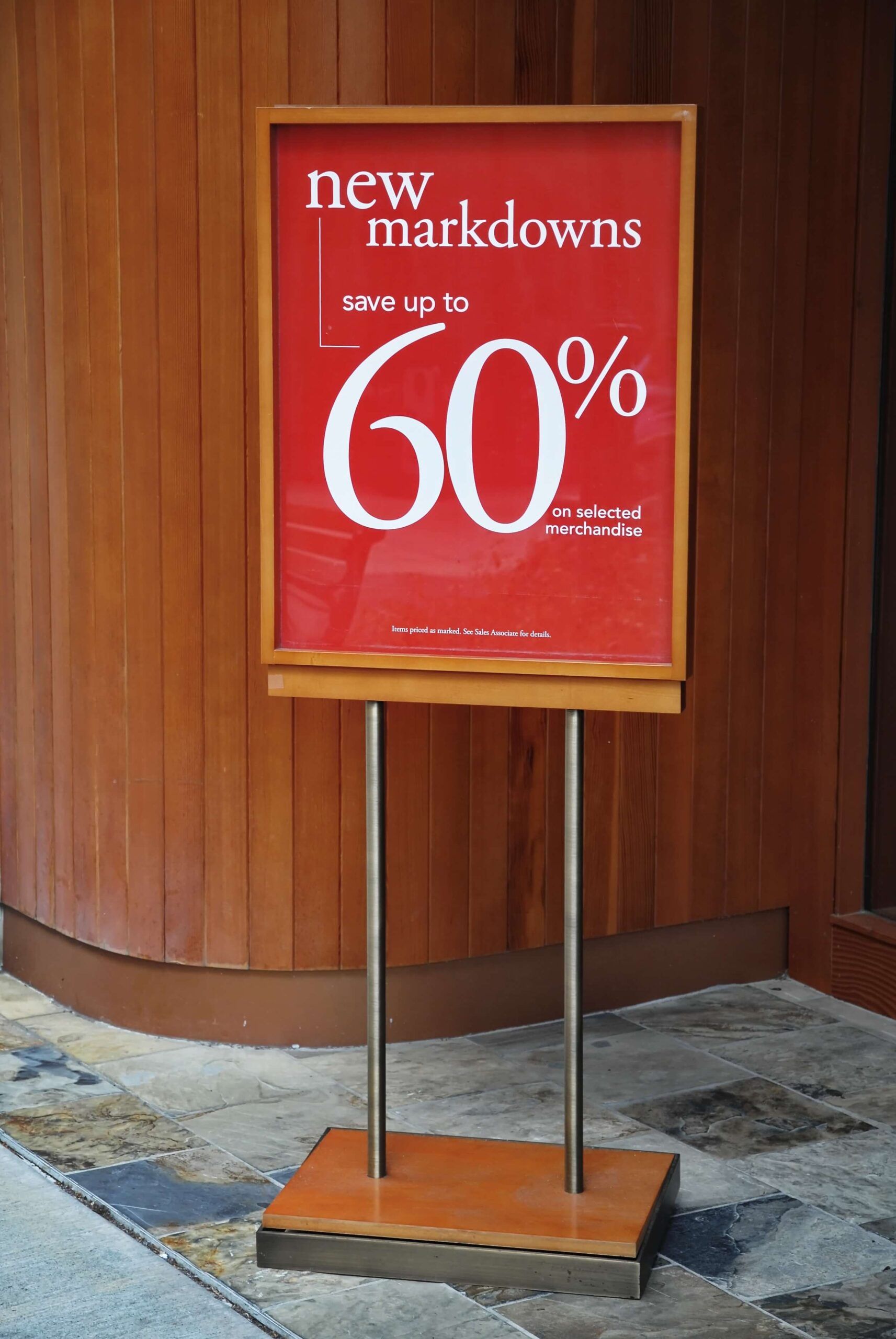 ed promotional signboard standing outside a store announcing new markdowns of up to 60% on selected merchandise.